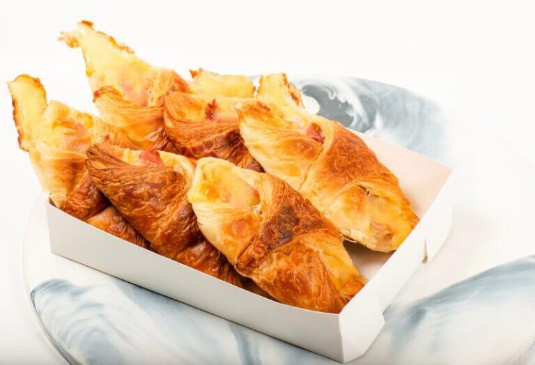 Croissants dorés garnis de jambon et fromage, saupoudrés de poivre de Sichuan, prêts à déguster